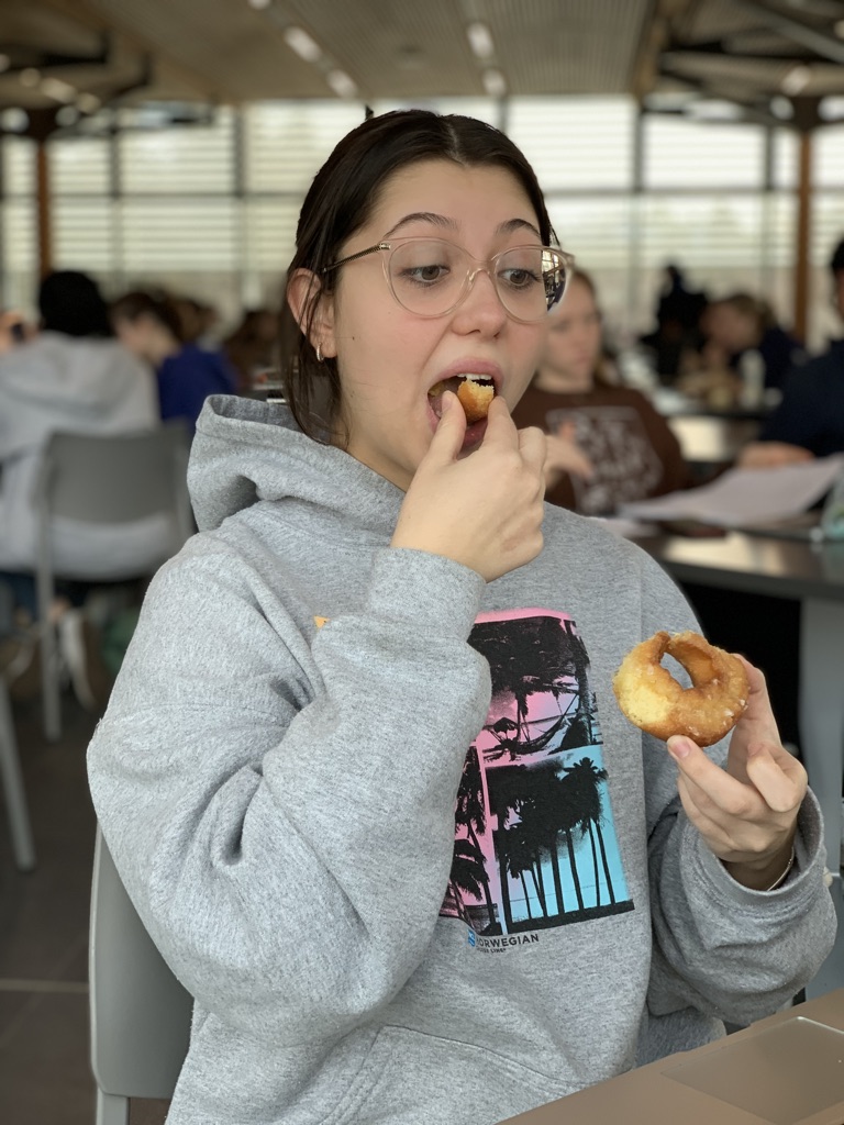 A picture of me in portrait mode taking a piece off the sour cream glaze donut and beginning to eat it.