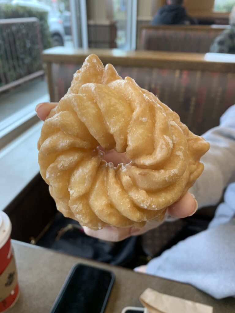 A honey cruller donut that Sophie is holding up to display it's rather cool but weird donut shape.