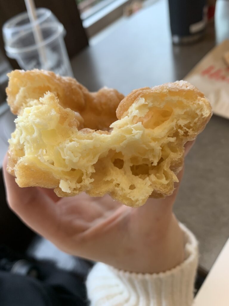 A honey cruller donut biten to where you see the inside of the donut