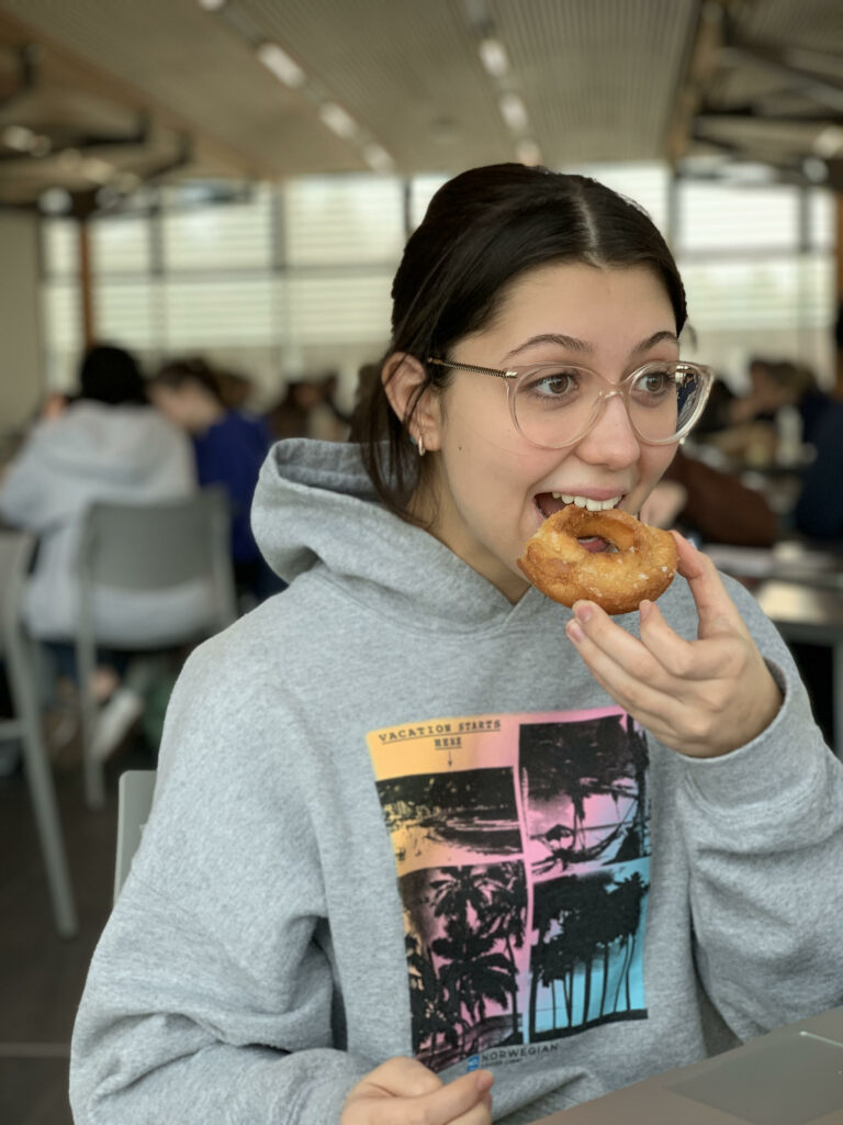 A picture of me in portrait mode taking a bite out of the donut for the first time.